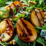 Caramelized pear salad with blue cheese, walnuts, and balsamic glaze on a white plate